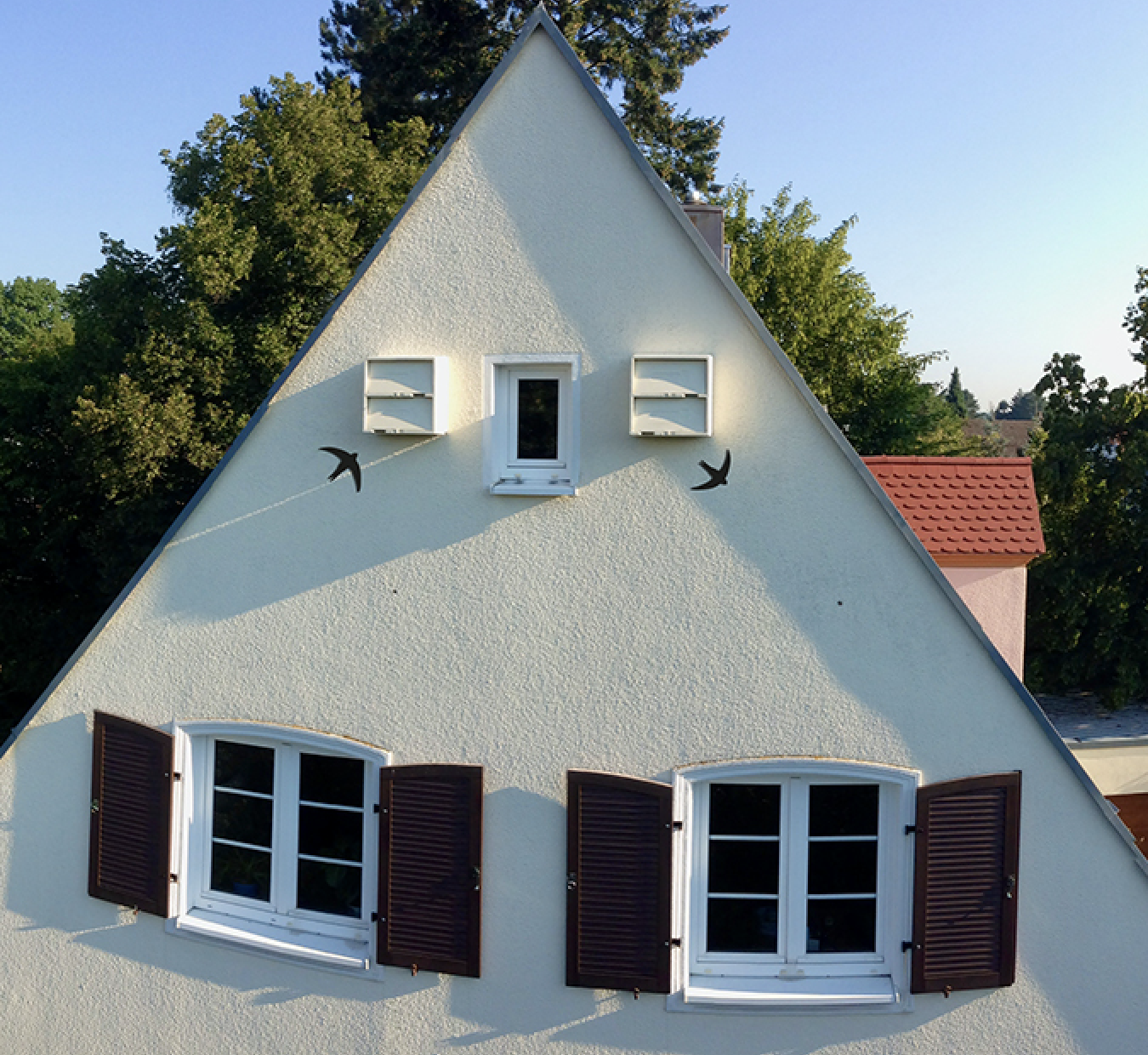 zwei Mauerseglerkästen im Giebel von einem Haus Mauerseglerkasten an gelber Hausfassade mit Zeigevogel